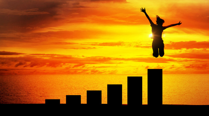 A mid-air figure in shadow with orange/yellow sunset, clouds, and water in the background
